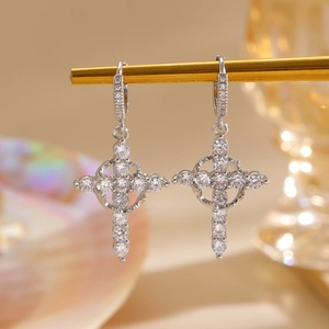 Macro shot of silver cross earrings with sparkling white diamonds on a metal stand