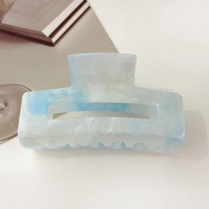 Detail of square hair claw clip with blue and white marble texture and gold glitter