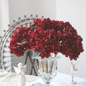 Close-up of dark red vintage hydrangea artificial flowers in an embossed glass vase