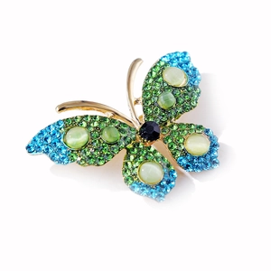 Detail of butterfly brooch with green rhinestones and cat-eye stones on gold alloy