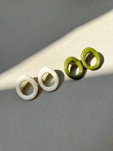 Close-up of geometric resin oval earrings in cream white and olive green colors