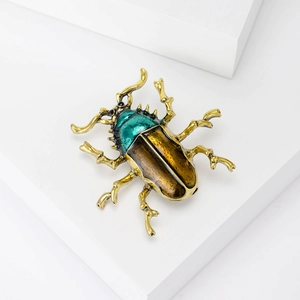 Vintage beetle brooch with green and brown enamel on a white geometric platform