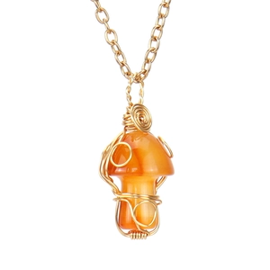 Macro detail of wire-wrapped orange agate mushroom pendant on a delicate gold chain