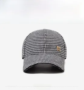 Détail de la casquette de baseball en pied-de-poule avec lettre M en métal doré