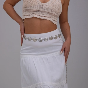 Detail of silver alloy waist chain with spiral textured metal discs on a white dress