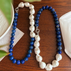 Detail of baroque pearl and blue lapis lazuli necklace on a rustic wooden surface