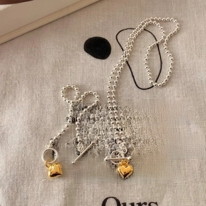 Detail of silver bead necklace with golden heart pendant and T-bar toggle closure