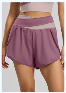 Détail de la taille haute croisée sur un short de sport 2-en-1 avec poche latérale