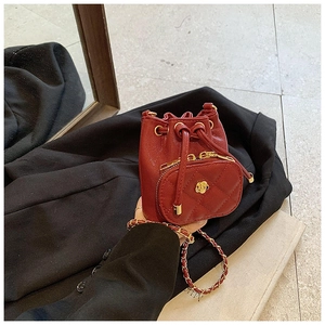 Detail of red quilted mini bucket bag with gold flower clasp and chain strap