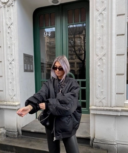 Detailed view of women's black oversized satin bomber jacket with street style aesthetics