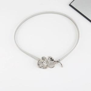 Detail of silver metallic spring belt with a delicate rose flower buckle on white surface