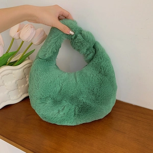 Green fuzzy plush handbag for women with single handle on wooden table next to tulips