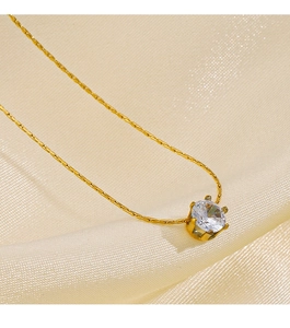 Detailed view of gold necklace with six-prong set round cubic zirconia on silk