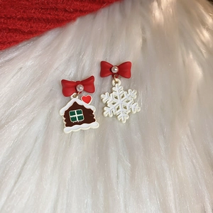 Detail of Christmas earrings featuring a gingerbread house and white snowflake with pearls