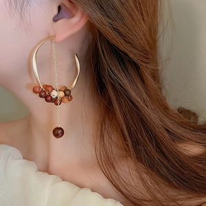 Macro shot of sandalwood bead hoop earrings with long golden chain tassels on model