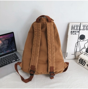 Rear view of brown canvas backpack showing adjustable shoulder straps and padded back design