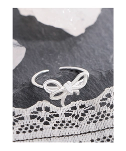 Macro view of silver S925 bow knot ring on black rock with delicate lace detail