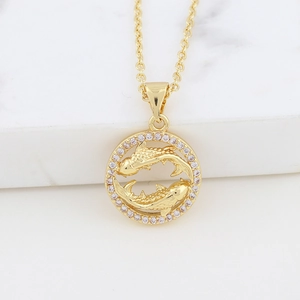 Detail of golden koi fish pendant with sparkling stones on white marble surface