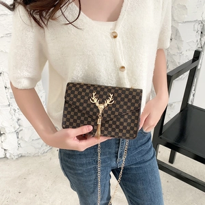 Vintage brown crossbody bag with gold deer head detail and chain strap on a model