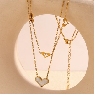 Detail of double-layer gold necklace with open heart and white shell heart pendant