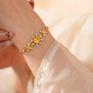 Makroaufnahme eines Vintage-Goldarmbands mit gelbem ovalem Edelstein und Zirkonia-Blüten
