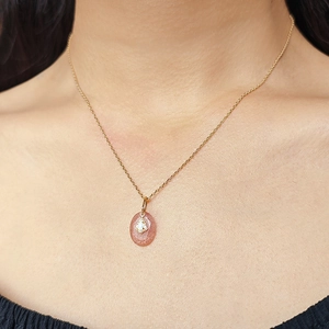 Close-up of a natural strawberry crystal pendant on a gold 925 silver chain worn by a model