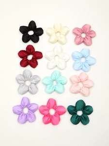 Flat lay showing 12 colors of elegant satin flower hair scrunchies in silk-like fabric