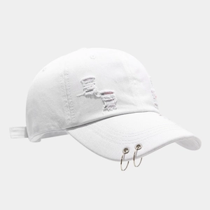 Close-up of white denim baseball cap featuring distressed holes and dual silver metal rings