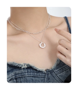 Detail of layered S925 silver necklace with paperclip chain and lava circle pendant