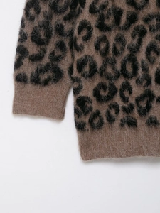 Vue macro du pull en maille léopard montrant la texture du tissu et les poignets côtelés