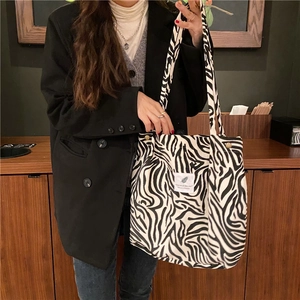 Fashionable zebra print tote bag with stylish text patch shown in a cozy cafe setting