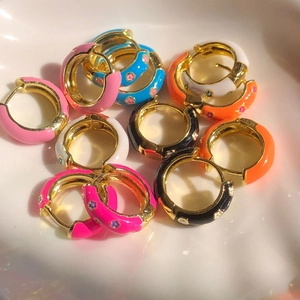 Classic gold hoop earrings with colorful enamel floral patterns in a ceramic tray