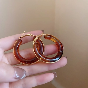 Detailed view of large amber resin hoop earrings with elegant gold metal fasteners