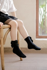 Detail of black lace ruffle cotton socks with large silk bow for little girls