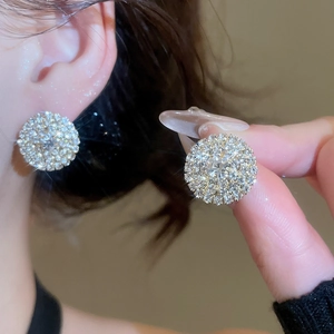 Macro detail of round silver pave earrings with central diamond on model