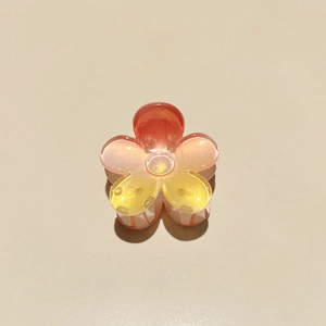 Macro view of plumeria hair claw with acrylic gradient petals and glitter finish