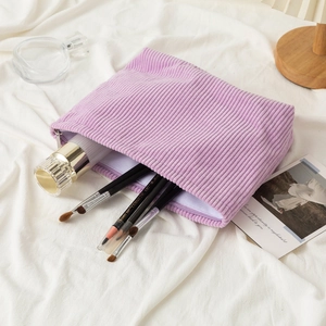 Purple corduroy cosmetic bag for makeup brushes on white fabric with soft lighting