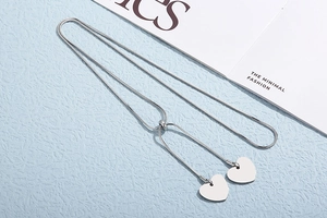 Detail of silver snake chain necklace with dual heart pendants and adjustable slider clasp