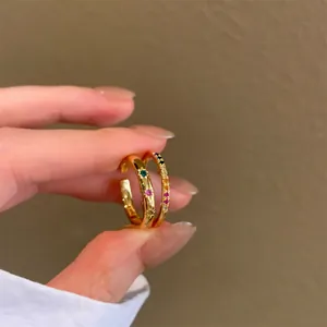 Dettaglio di anelli a stella dorati con zirconi multicolore e finitura lucida