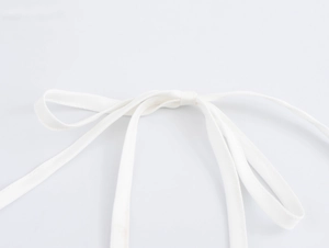 Detail of the soft white fabric tie bow on a striped halter dress with smooth texture