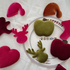 Assorted Christmas velvet patches in festive shapes like reindeer and trees on white cloth