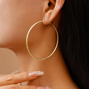 Minimalist gold hoop earring with textured metallic finish on female model