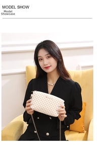 Detail of yellow checkerboard pattern crossbody bag with gold chain strap on model