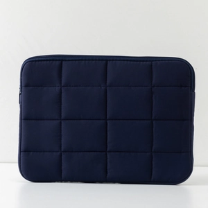 Detail of dark blue quilted laptop sleeve featuring high-quality polyester and zipper closure