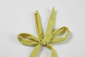 Close-up of a vibrant yellow halter tie detail with satin finish on backless summer dress