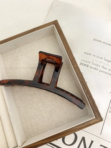 Macro view of a large amber-patterned hair claw clip on an elegant wooden tray