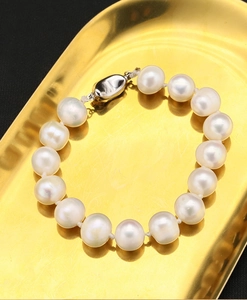 Detailed macro view of high-lustre natural white pearls on a metallic golden tray