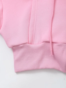 Detail of pink hoodie showing ribbed hem, drawstring and knit texture of the fabric