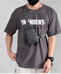 Front view of a dark gray waterproof chest bag worn by a model for a modern street look