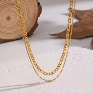 Chic double layered gold stainless steel necklace with flat Figaro chain on textured stone